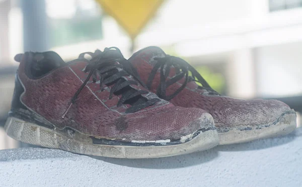 Ön verandadaki beton sütundaki yıpranmış spor ayakkabı.