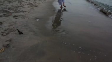 Tanımlanamayan bir kadın plajda yalınayak geziniyor..