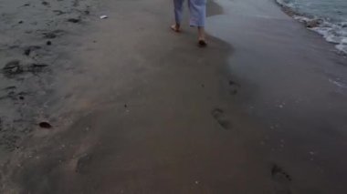 Tanımlanamayan bir kadın plajda yalınayak geziniyor..