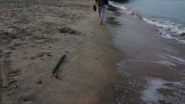 Tanımlanamayan bir kadın plajda yalınayak geziniyor..