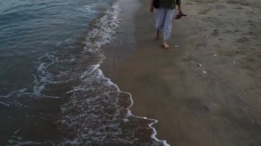 Tanımlanamayan bir kadın plajda yalınayak geziniyor..