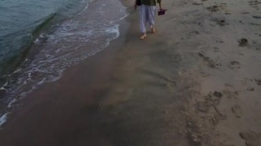 Tanımlanamayan bir kadın plajda yalınayak geziniyor..