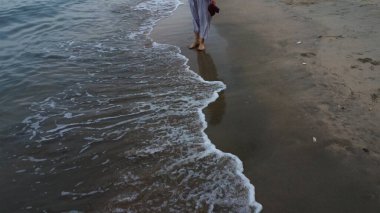 Tanımlanamayan bir kadın plajda yalınayak geziniyor..