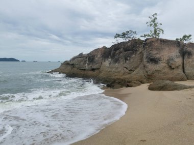 daytime scene of boulders along the beach.
