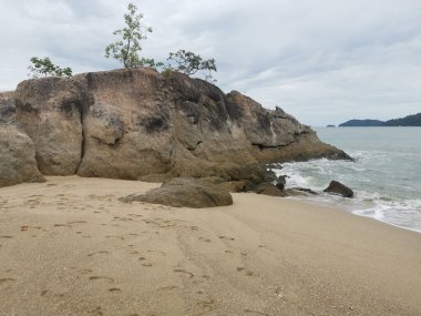 daytime scene of boulders along the beach.