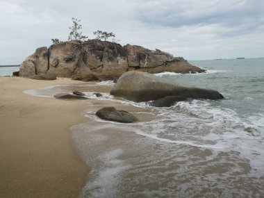 daytime scene of boulders along the beach.