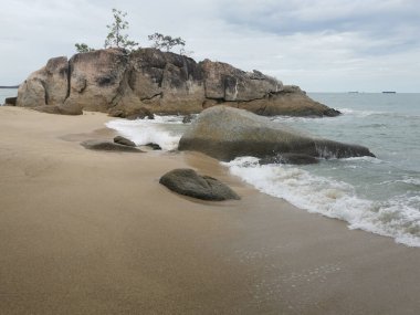 daytime scene of boulders along the beach.