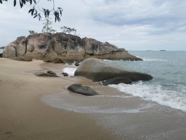 daytime scene of boulders along the beach.