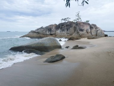 daytime scene of boulders along the beach.