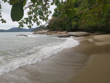 daytime scene of boulders along the beach.