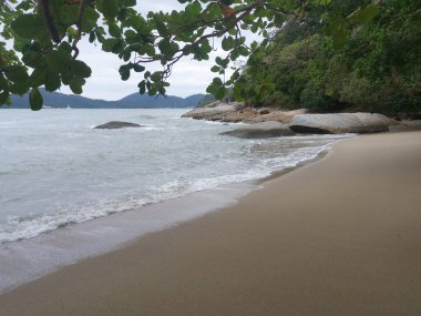 daytime scene of boulders along the beach.