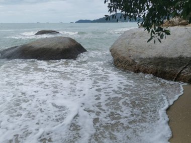daytime scene of boulders along the beach.