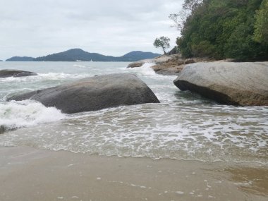 daytime scene of boulders along the beach.