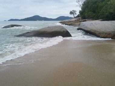 daytime scene of boulders along the beach.