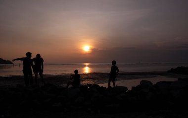 unrecognizable people standing in the dark viewing the evening setting sun.