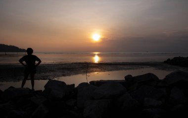 unrecognizable people standing in the dark viewing the evening setting sun.