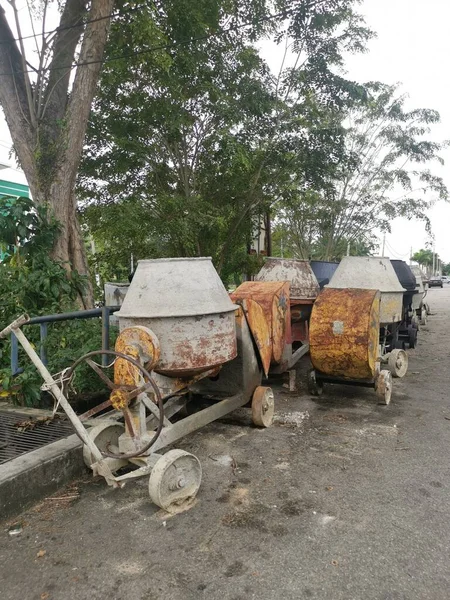 several old cement mixer machines left by the roadside.