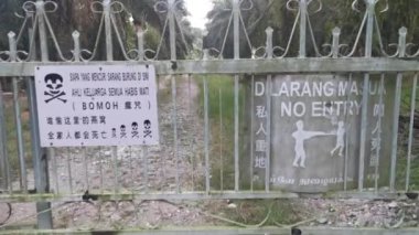 Signboards outside the entrance gate written in Malay and Mandarin languages prohibit trespass into the private property