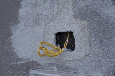 3 electric wires laying out from the concrete wall