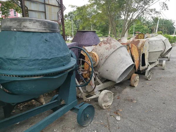 several old cement mixer machines left by the roadside.