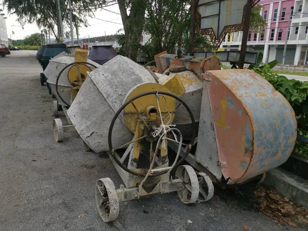 several old cement mixer machines left by the roadside.