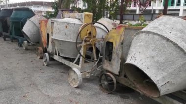 several old cement mixer machines left by the roadside.