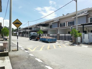 Perak, Malezya. 27 Eylül 2022: Çöp kamyonunun devrildiği sokak manzarası Taman Mas Konutu 'na taşınmak üzere beton döküntülerle dolu metal çöp konteynırını kancaya takıyor.