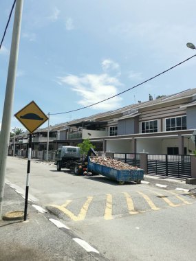 Perak, Malezya. 27 Eylül 2022: Çöp kamyonunun devrildiği sokak manzarası Taman Mas Konutu 'na taşınmak üzere beton döküntülerle dolu metal çöp konteynırını kancaya takıyor.