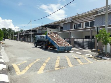 Perak, Malezya. 27 Eylül 2022: Çöp kamyonunun devrildiği sokak manzarası Taman Mas Konutu 'na taşınmak üzere beton döküntülerle dolu metal çöp konteynırını kancaya takıyor.