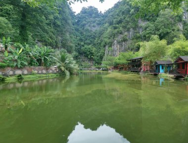 Perak, Malezya. 30 Eylül 2022: Ipoh 'taki Qing Xin Ling Eğlence ve Kültür Köyü' nde göl boyunca inşa edilen ahşap evlerin güzel yeşillik manzarası