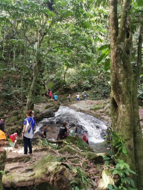 Perak, Malezya. 30 Eylül 2022: Kg Ulu Geruntum Şelalesi, Gopeng 'daki şelalenin ipini çekmek için sıralarını beklerken veya kendilerini nehre daldıran kalabalık
