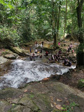 Perak, Malezya. 30 Eylül 2022: Kg Ulu Geruntum Şelalesi, Gopeng 'daki şelalenin ipini çekmek için sıralarını beklerken veya kendilerini nehre daldıran kalabalık