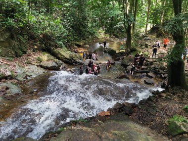 Perak, Malezya. 30 Eylül 2022: Kg Ulu Geruntum Şelalesi, Gopeng 'daki şelalenin ipini çekmek için sıralarını beklerken veya kendilerini nehre daldıran kalabalık