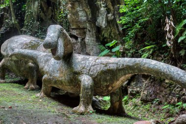 Perak, Malezya. 30 Eylül 2022: İki büyük orman kökü, Qing Xin Ling Dinlenme ve Kültür Köyü 'nde Sauropod şeklinde bir dinozorla birlikte topraktan filizleniyor.