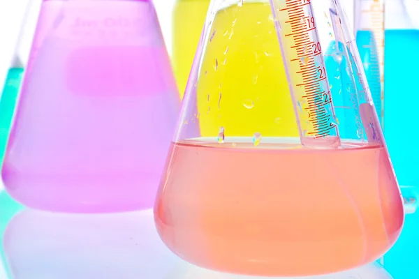 Volumetric laboratory glassware containing colored liquids — Stock Photo, Image