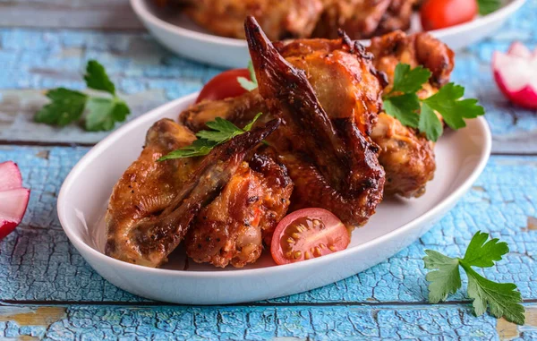 Mavi arka planda beyaz bir tabakta kızarmış tavuk kanadı.