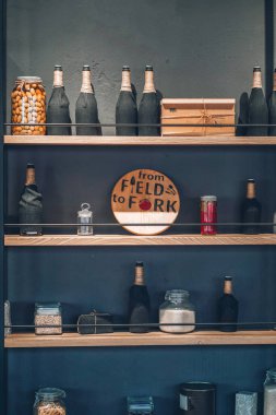 Şişeler, kavanozlar ve arka plandaki ahşap rafta duran cam mutfak aletleri. İç nesne fotoğrafı.