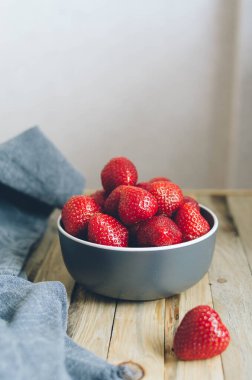 Tabakta taze olgun çilek ve keten havlu. Köyde sağlıklı bir kahvaltı için büyük kırmızı meyveler.