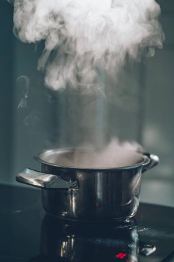 The process of cooking soup in a pot on an electric stove. Autumn in the kitchen. Steam rising from a pot in the cuisine