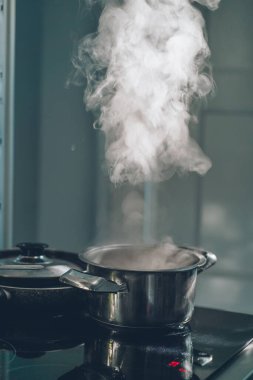 The process of cooking soup in a pot on an electric stove. Autumn in the kitchen. Steam rising from a pot in the cuisine