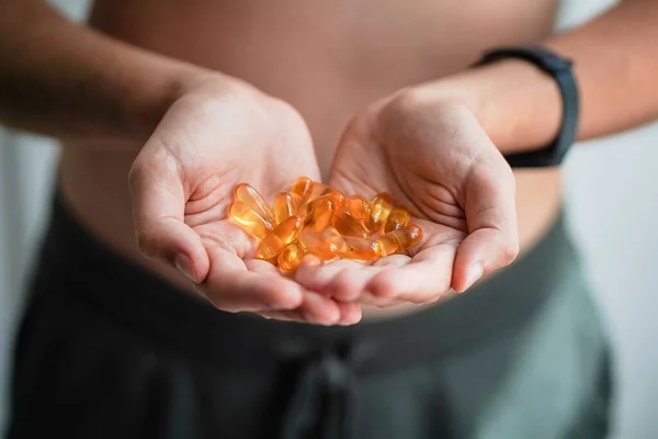 A handful of vitamins in the hands of a young man. Bright Omega-3 capsules. Medicinal product of animal origin. Fish oil source of vitamins A and D