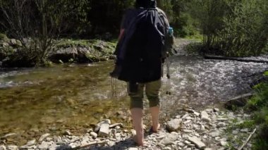 A barefoot mountaineer crosses the river