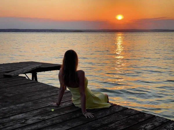 Woman Yellow Dress Sitting Wooden Pontoon Lake Admiring Sunset — Stockfoto