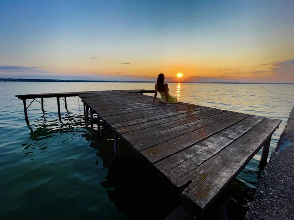 Woman Yellow Dress Sitting Wooden Pontoon Lake Admiring Sunset — Stockfoto