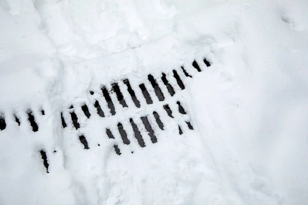 Storm sewer grate under the snow.