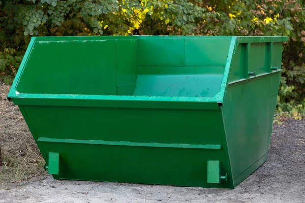 İnşaat için boş büyük yeşil metal konteynır ya da parktaki ağaçların arka planına karşı diğer büyük çaplı çöpler. Çevre koruma kavramı