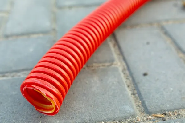 Red Corrugated Hose Electrical Wiring Paving Slabs Close Selective Focus — Stock Photo, Image