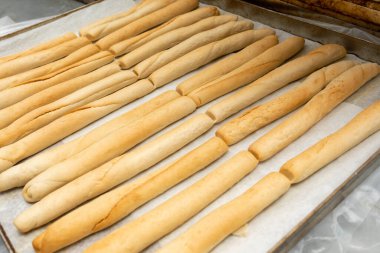 Uzun sıcak buğday çörekleri pişirdikten sonra metal tepside soğur. Fırın tepsisindeki taze ekmek.