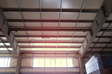 Endüstriyel binanın, deponun ve atölyenin tavanındaki metal yapılar. Fabrika binasının içinde endüstriyel arka plan için tavan kirişleri olan karmaşık kubbeli tavan. Renkli