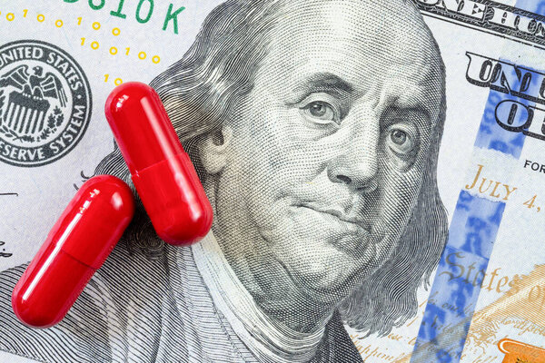 Health care, medical or pharmaceutical industry business or money concept. Red tablet pills on Franklin face on US dollar money banknotes